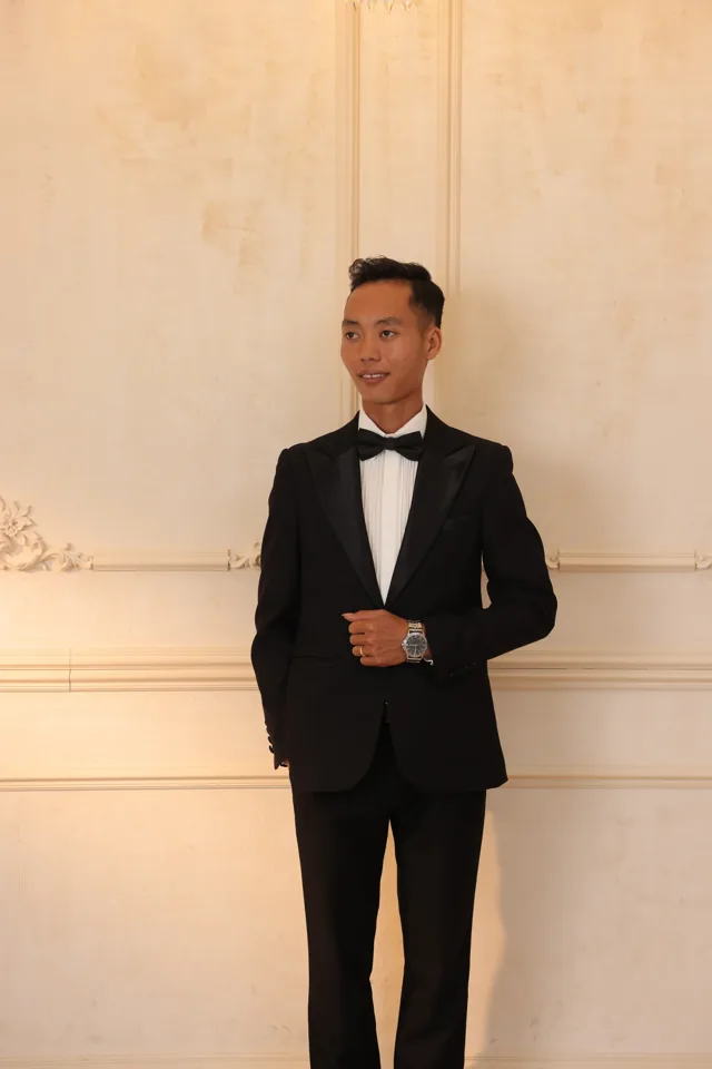 Lê Khoa trong bộ vest đen giữa không gian ánh vàng