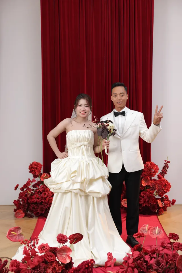 Khoa và Phương tạo dáng vui tươi trước phông đỏ