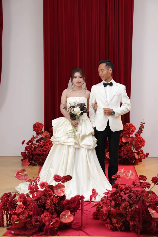 Khoa và Phương đứng bên nhau trên sân khấu hoa đỏ
